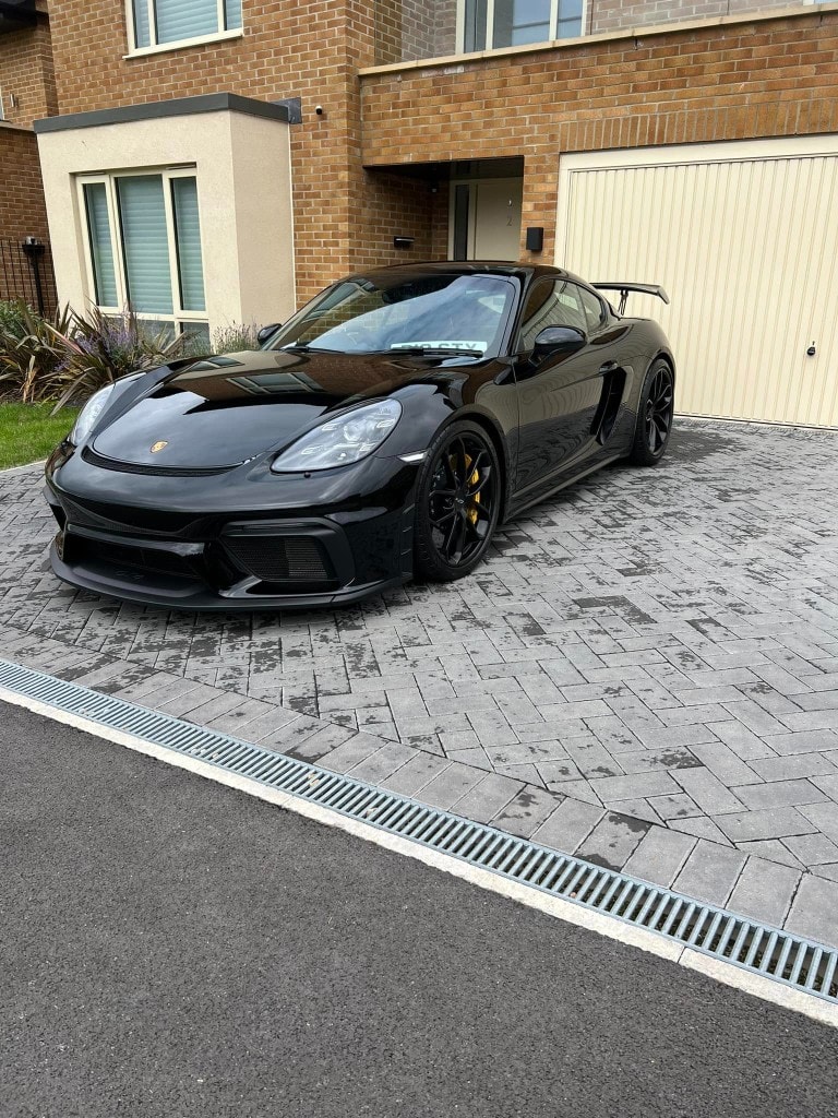 Black Porsche 718 Cayman GT4 detailed on a driveway