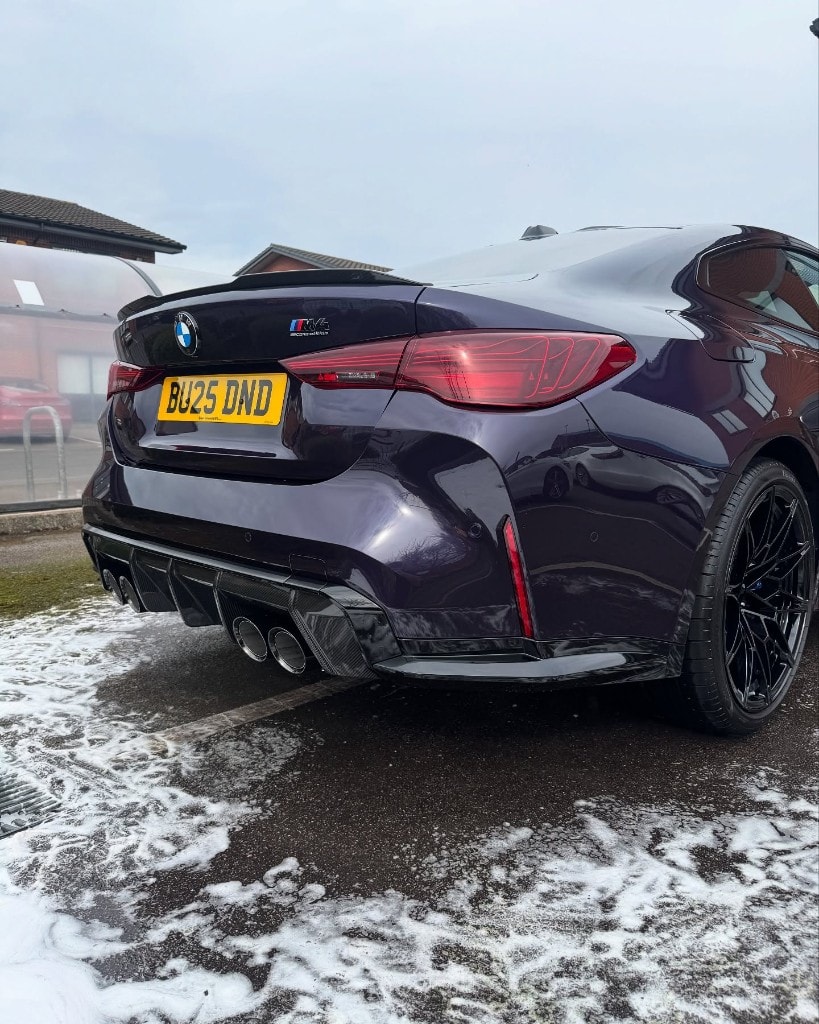 Purple BMW M4 Competition rear during a snow-foam wash